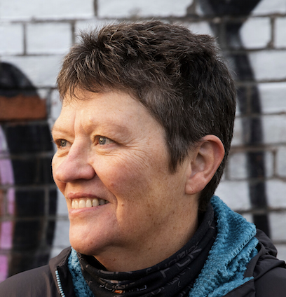 Smiling middle-aged man with gray hair and a light beard wearing a light gray collared shirt.