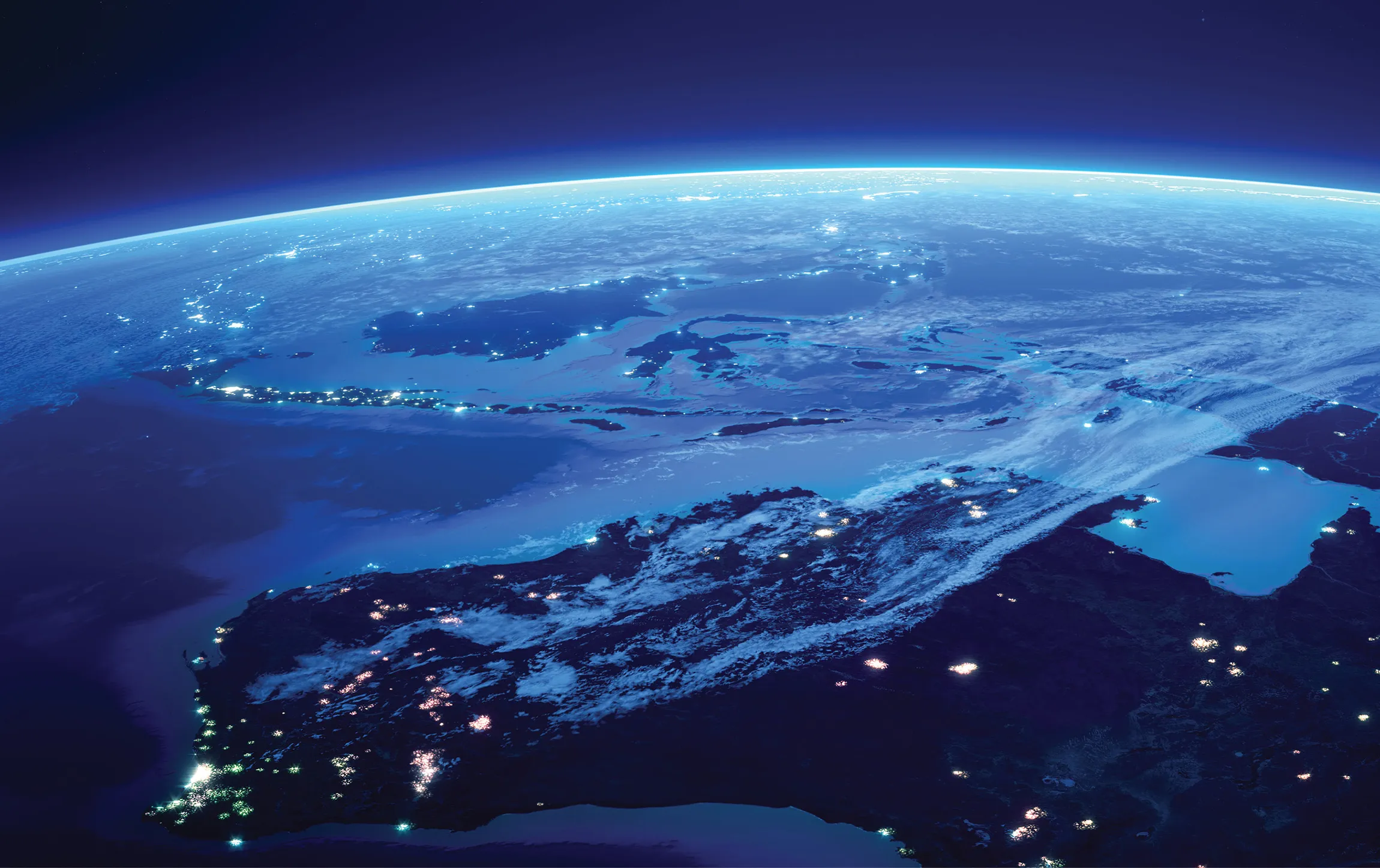 Night view of Southeast Asia from space showing illuminated cities and cloud cover over land and seas.