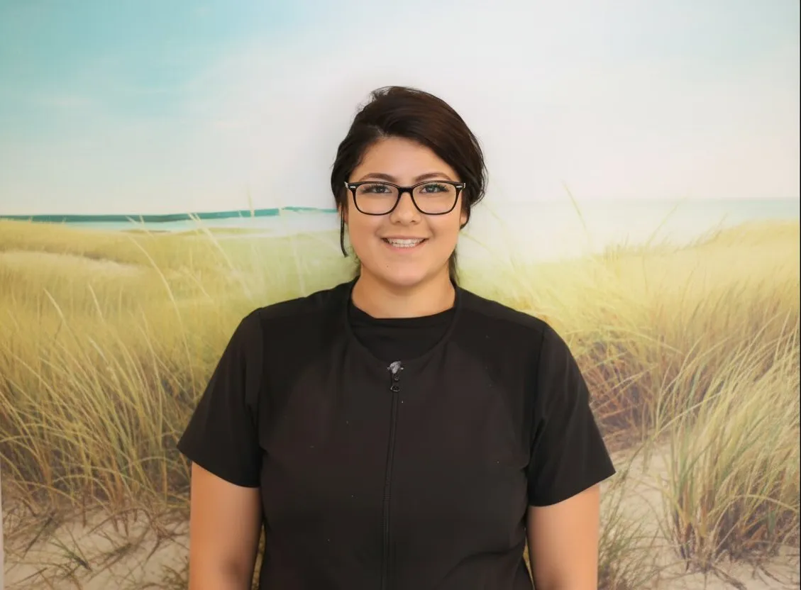 Smiling woman wearing glasses and black scrub top with a name badge.
