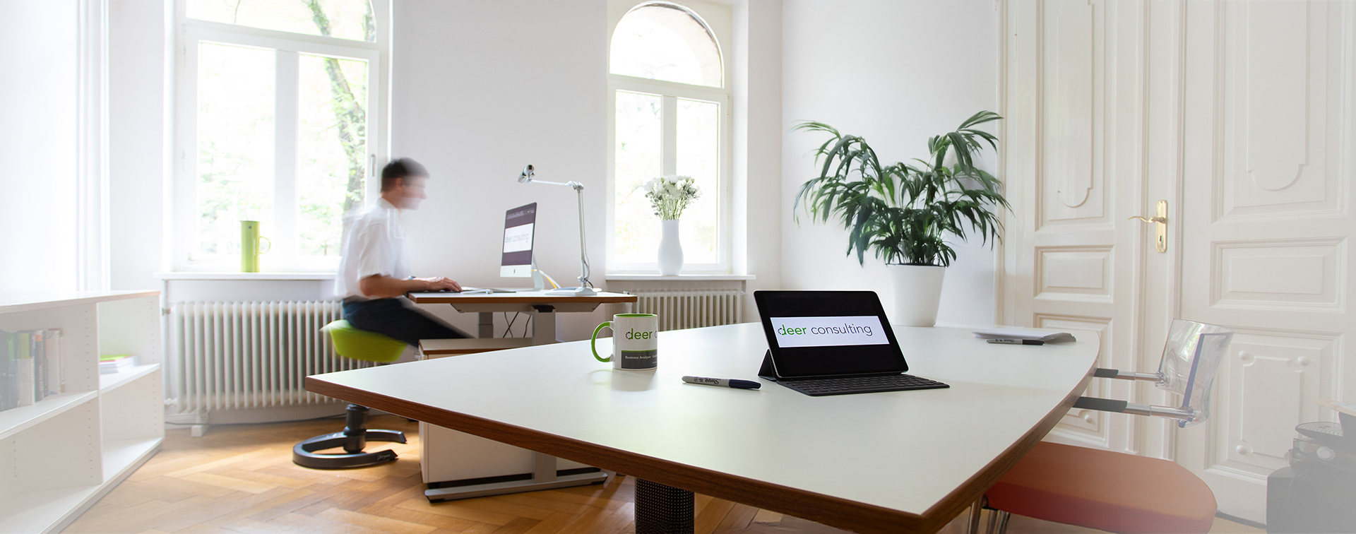 Headergrafik mit einer Person am Schreibtisch am PC am arbeiten.