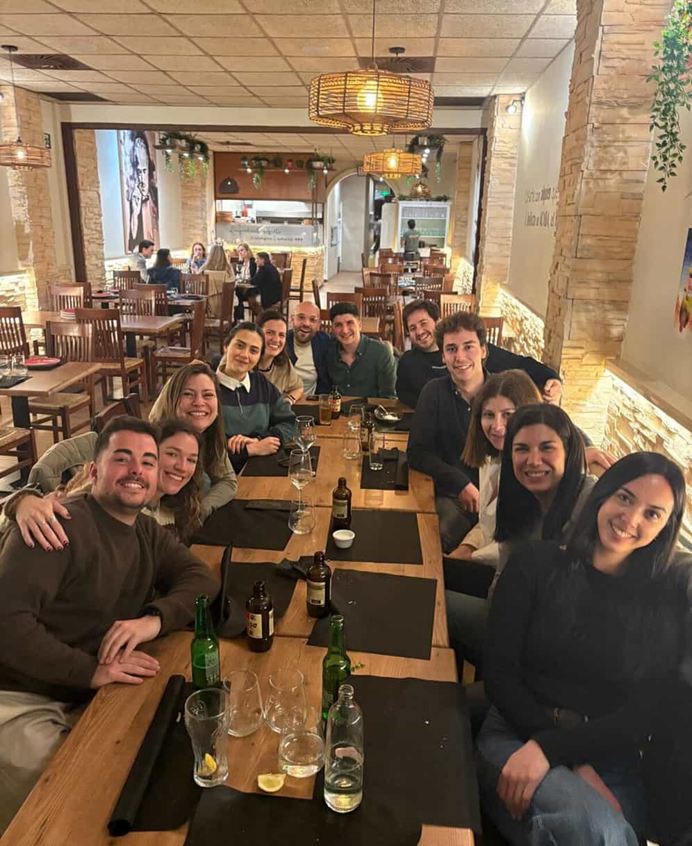Grupo de personas sonrientes sentadas alrededor de una mesa en un restaurante acogedor.