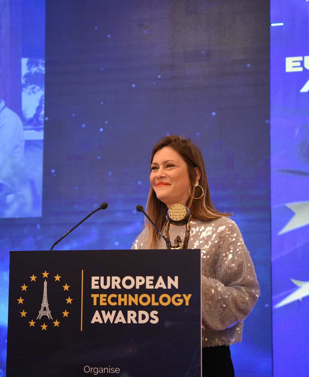 Mujer sonriente en un podio en los European Technology Awards con un trofeo en la mano.