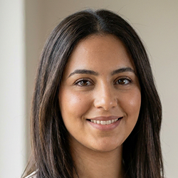 Portrait de Sarah AHKAF, coordinatrice administrative au sein de CSE Compétences, vêtue d'un chemisier beige clair devant un mur neutre.