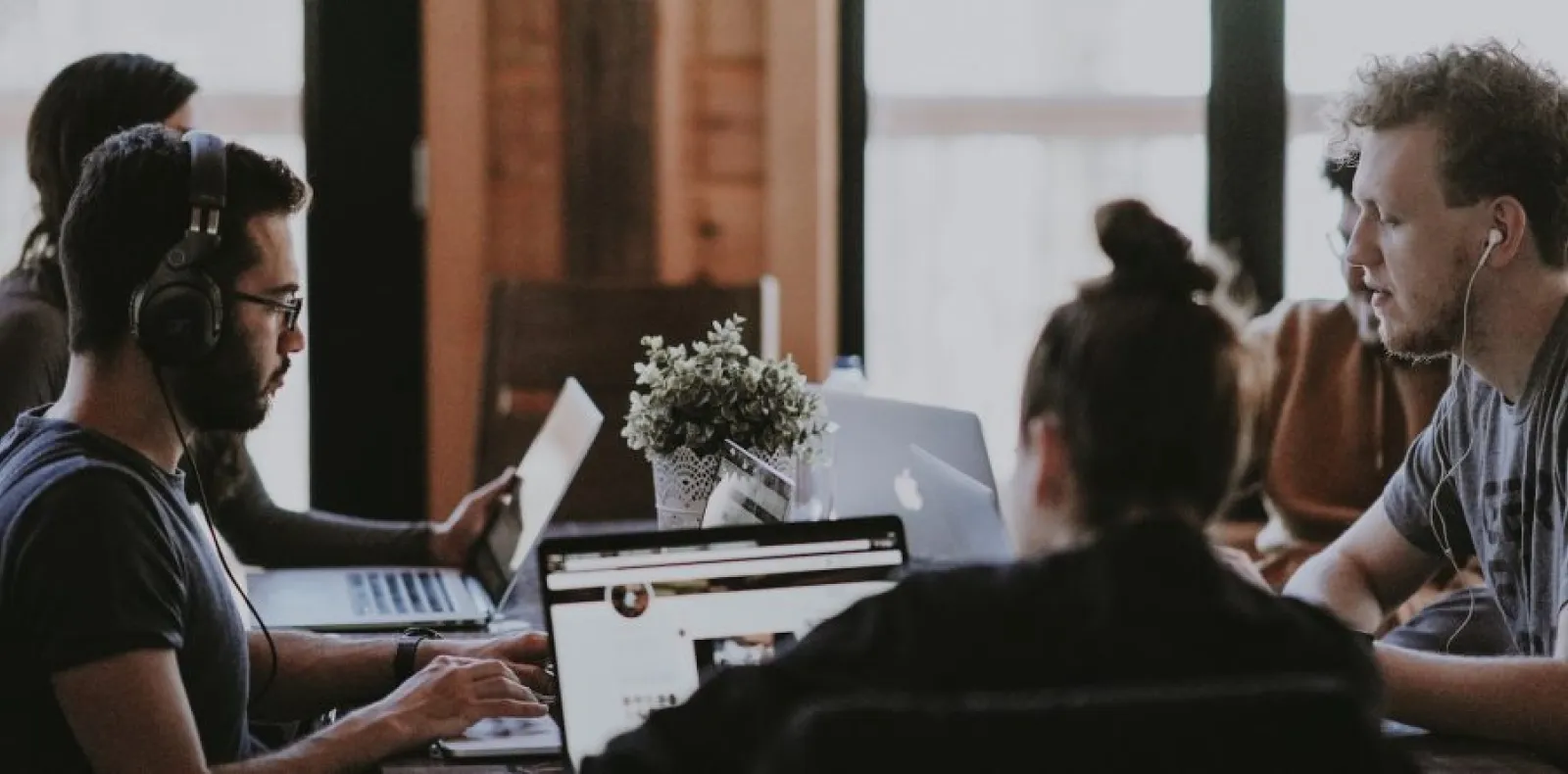 Worth Recruiting Toronto. Group of young professionals working on laptops around a table in a modern office space.