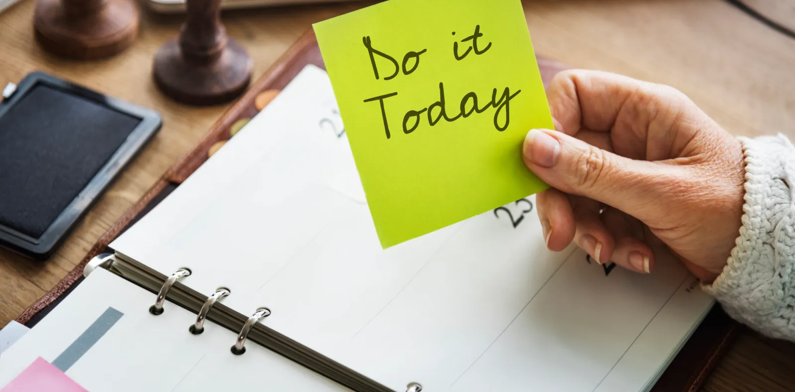 Worth Recruiting Toronto. Hand holding a green sticky note that says 'Do it Today' over an open planner on a wooden desk.