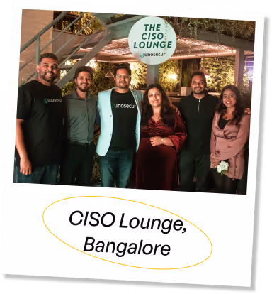 Six people posing and smiling under a sign that reads 'The CISO Lounge' with the Unosecur logo, at an event in Bangalore.