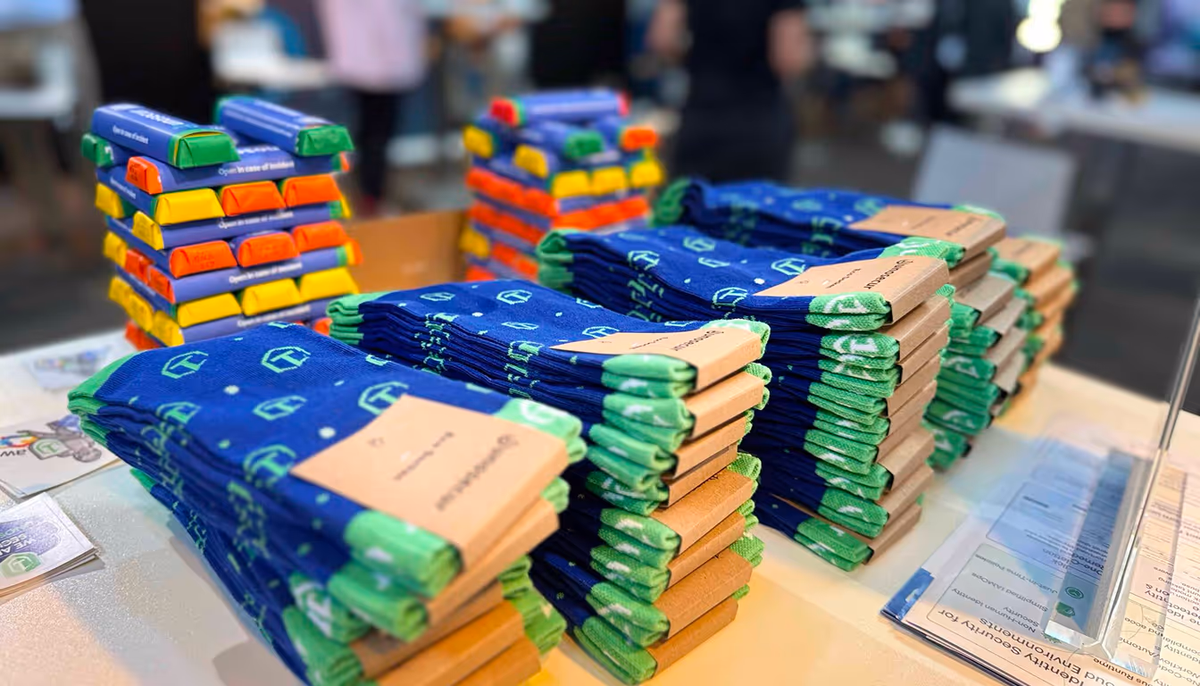 Stacks of blue and green folded socks alongside colorful wrapped chocolate bars on a table at a marketplace or event.