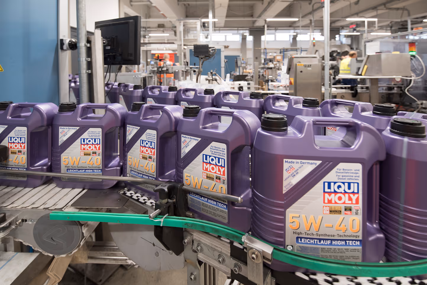 Multiple purple Liqui Moly 5W-40 oil containers on a conveyor belt in a factory setting.