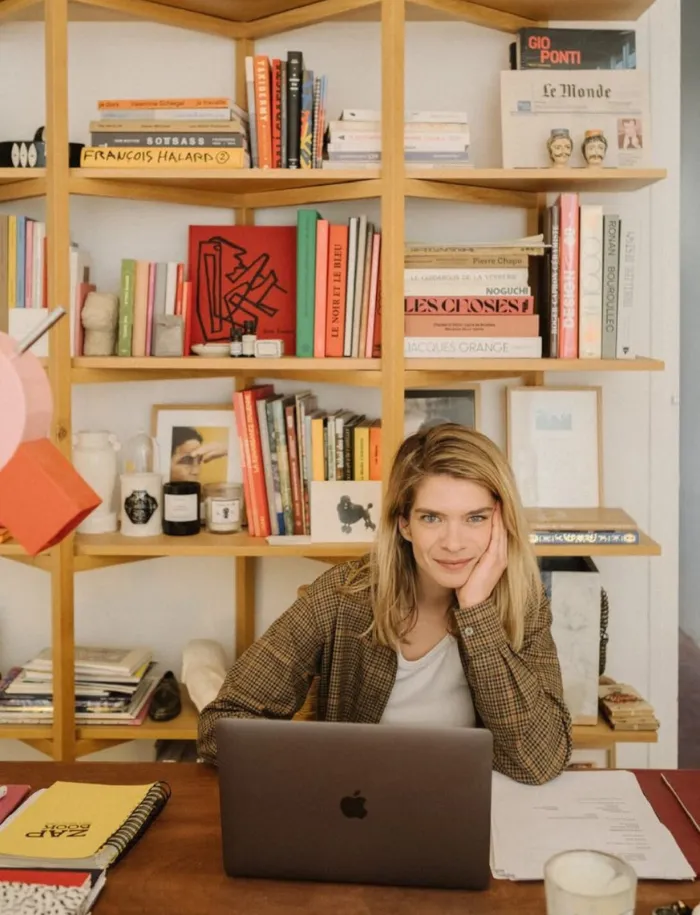 Portrait d'une femme à son bureau devant une bibliothèque design incluant la gazette Le Monde — Résidences urbaines Anchor.