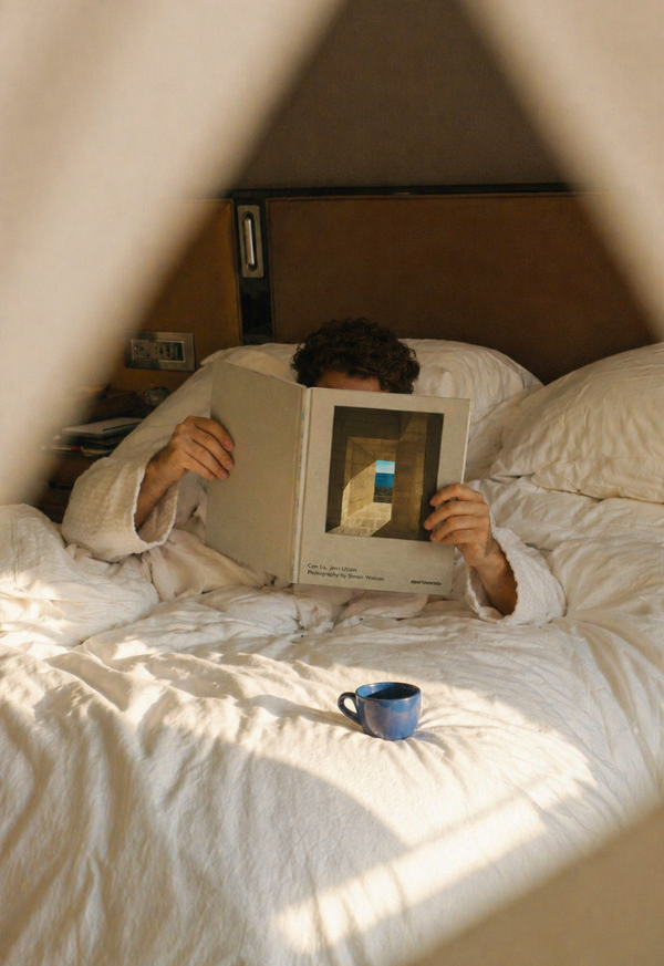 Moment de détente matinale avec un café dans un appartement Anchor, une personne lisant un magazine au lit.