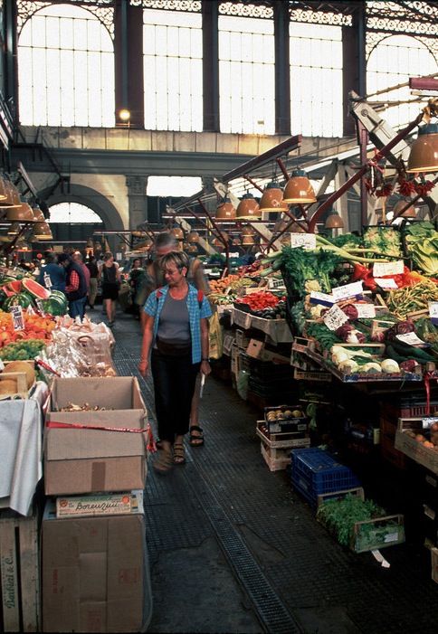 Intérieur d'un marché couvert historique (type Marché Central de Florence) avec des étals de produits régionaux. Gastronomie avec Anchor.