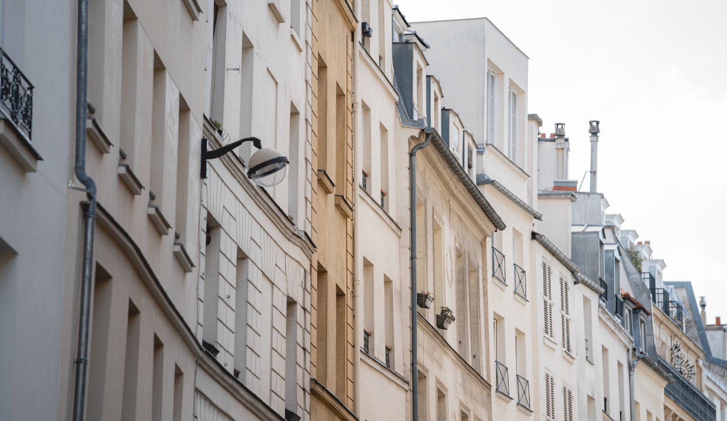 Façades d’immeubles anciens aux fenêtres et balcons étroits dans une rue urbaine calme.