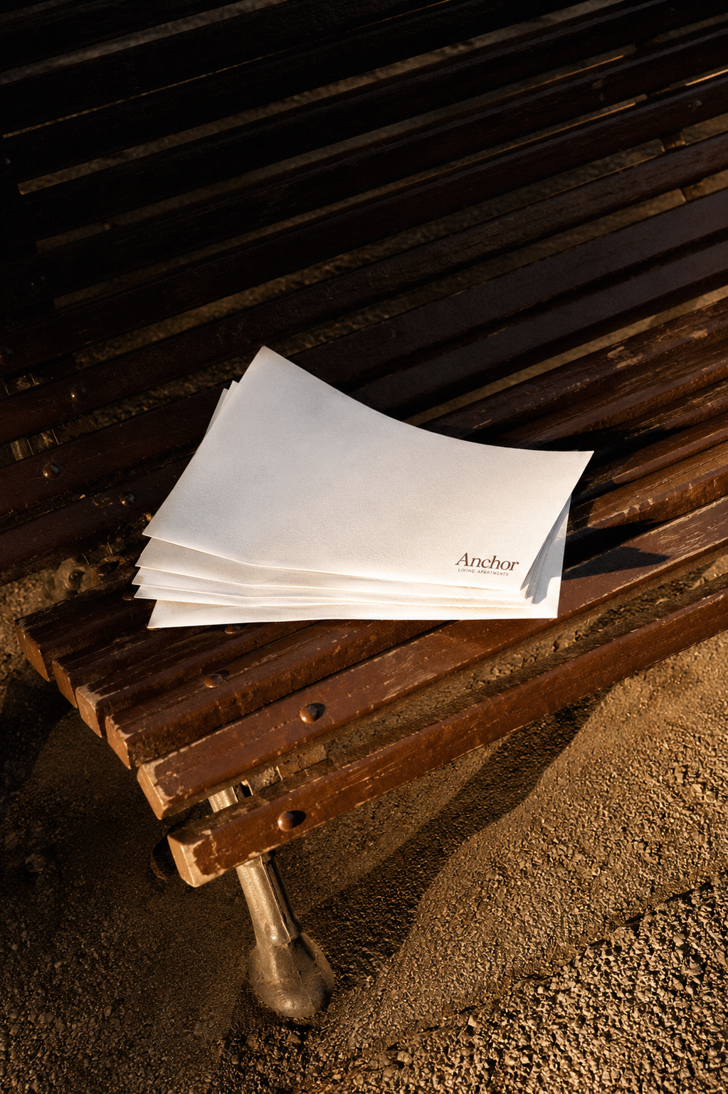Plusieurs enveloppes blanches empilées sur un banc en bois marron.