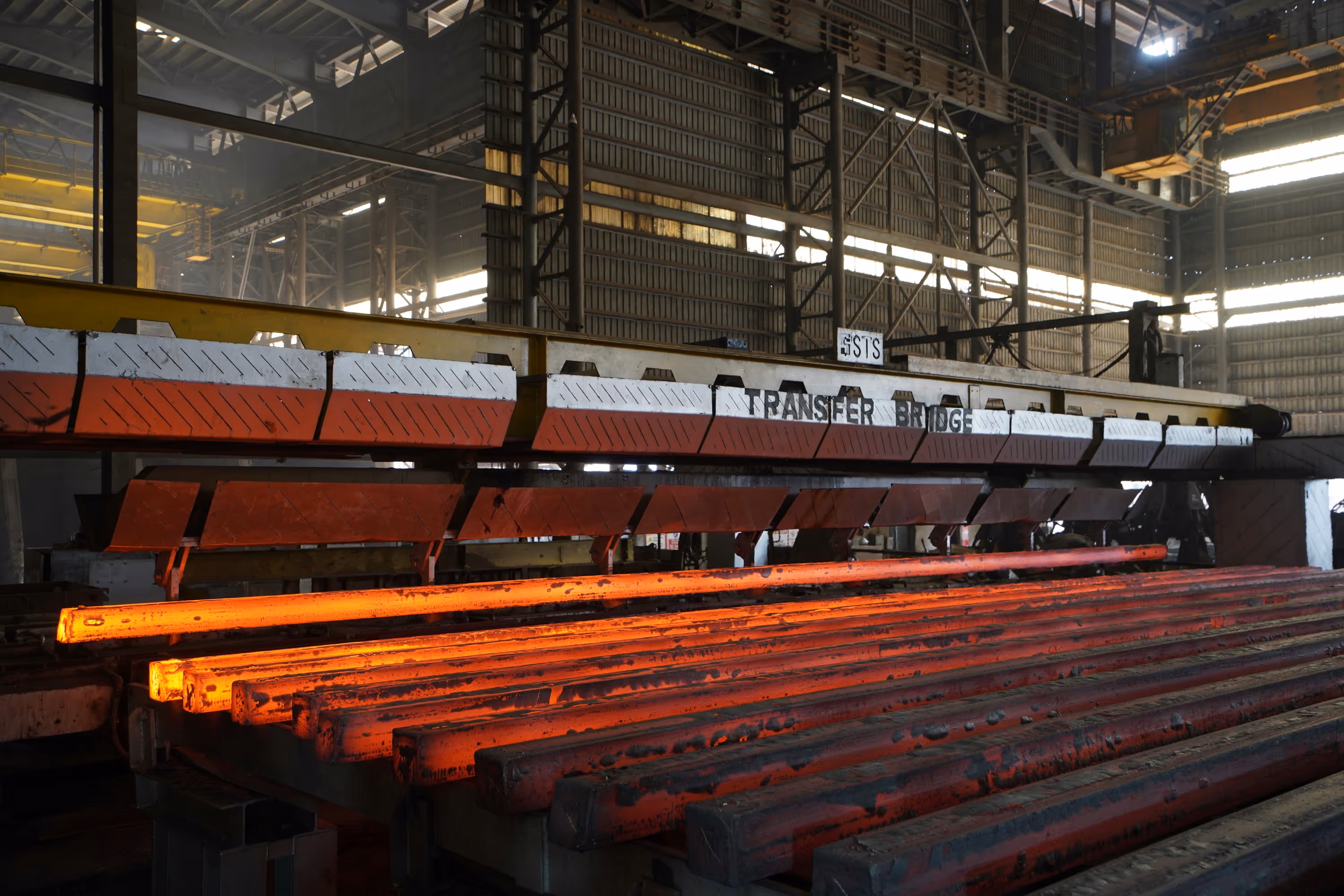 Hot steel rods being processed in a factory.