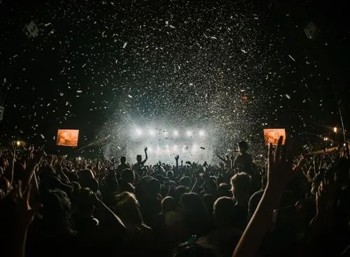 a crowd of people at a concert with confetti in the air