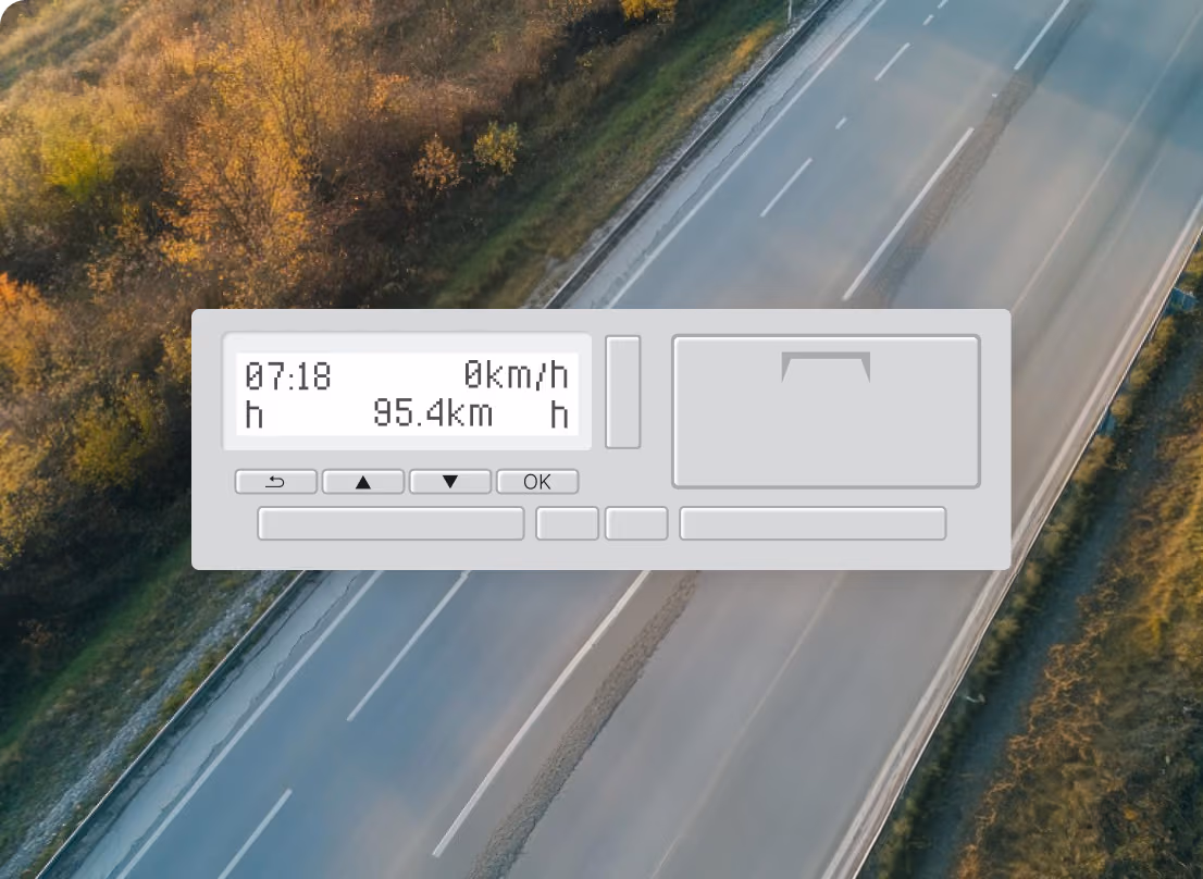 Digitale tachograaf met de tijd 07:18, snelheid 0 km/u en afstand 95,4 km, geplaatst boven een lege snelweg naast een bebost gebied.