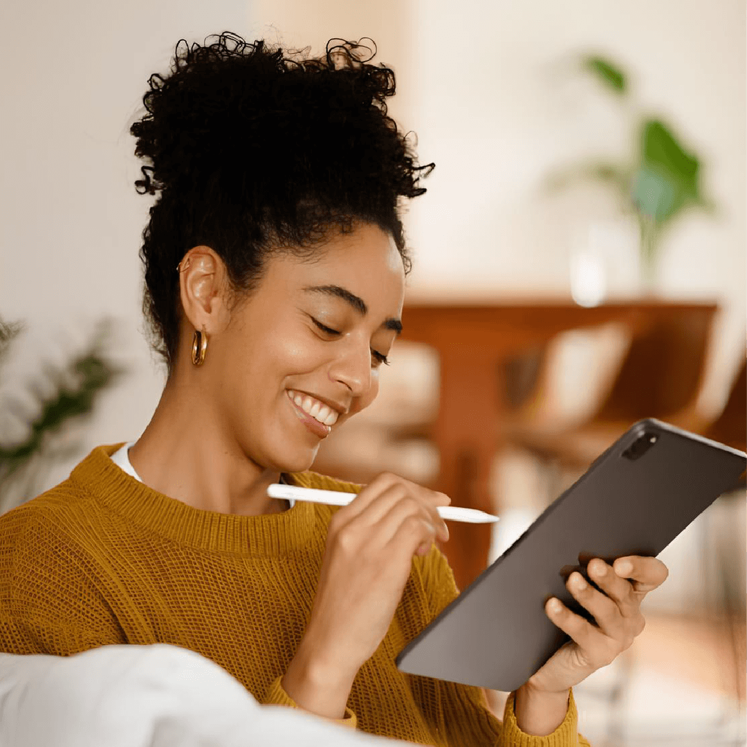 Smiling man with short curly hair wearing a dark suit and blue shirt against a gray background.