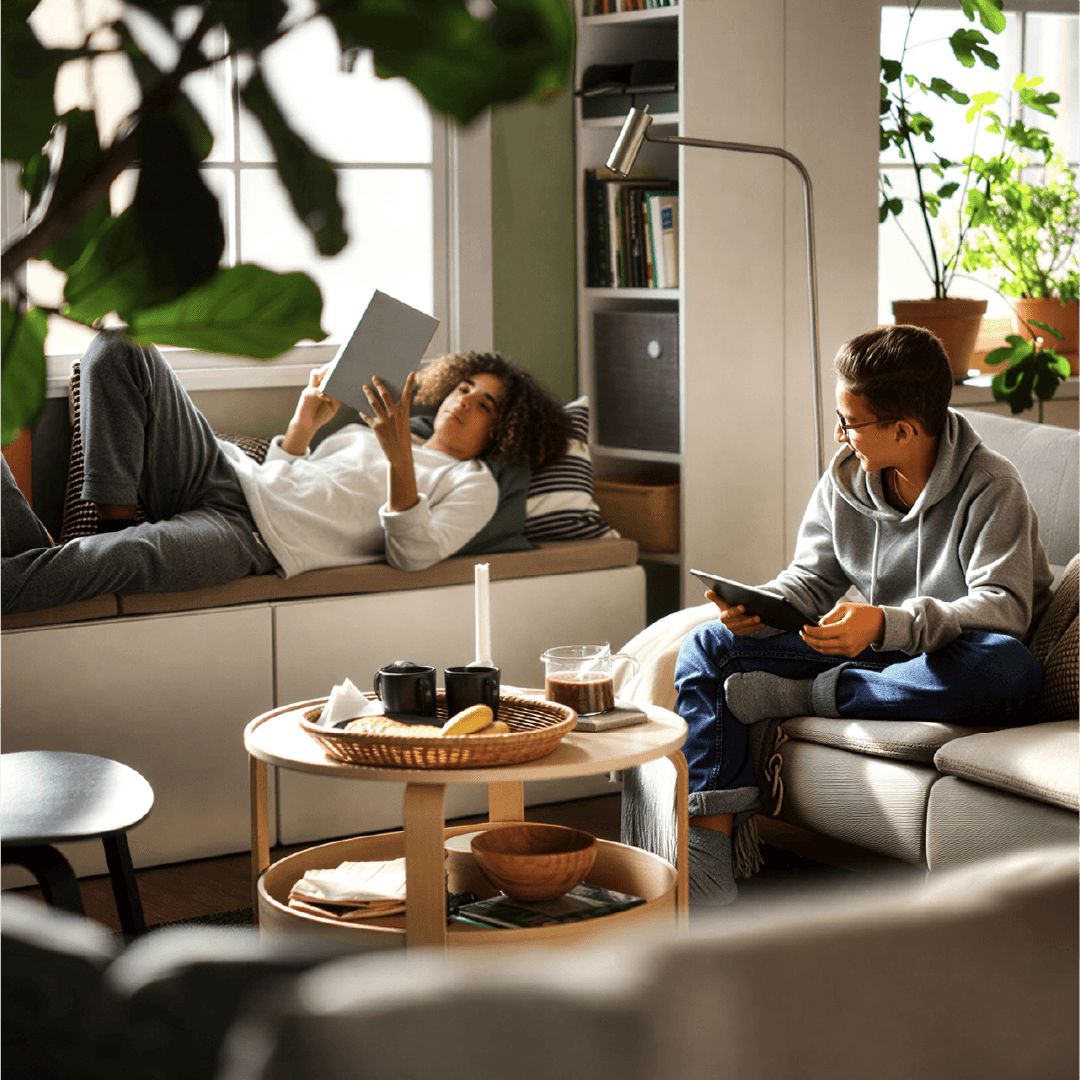 Smiling man with short curly hair wearing a dark suit and blue shirt against a gray background.