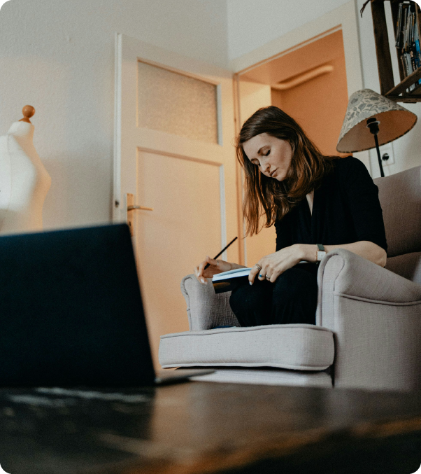 Smiling man with short curly hair wearing a dark suit and blue shirt against a gray background.