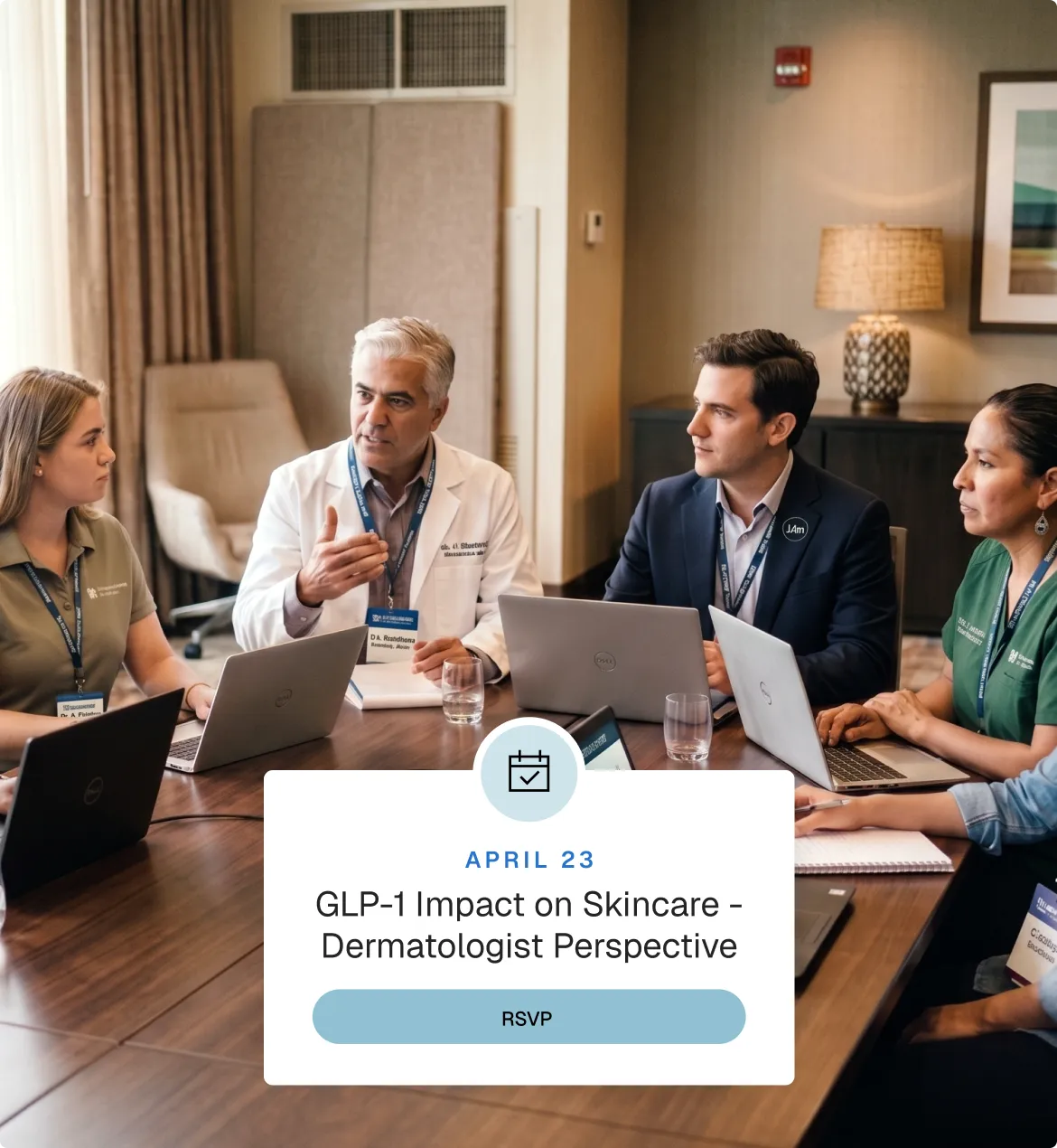 Four medical professionals seated around a conference table with laptops, engaged in a discussion in a meeting room.