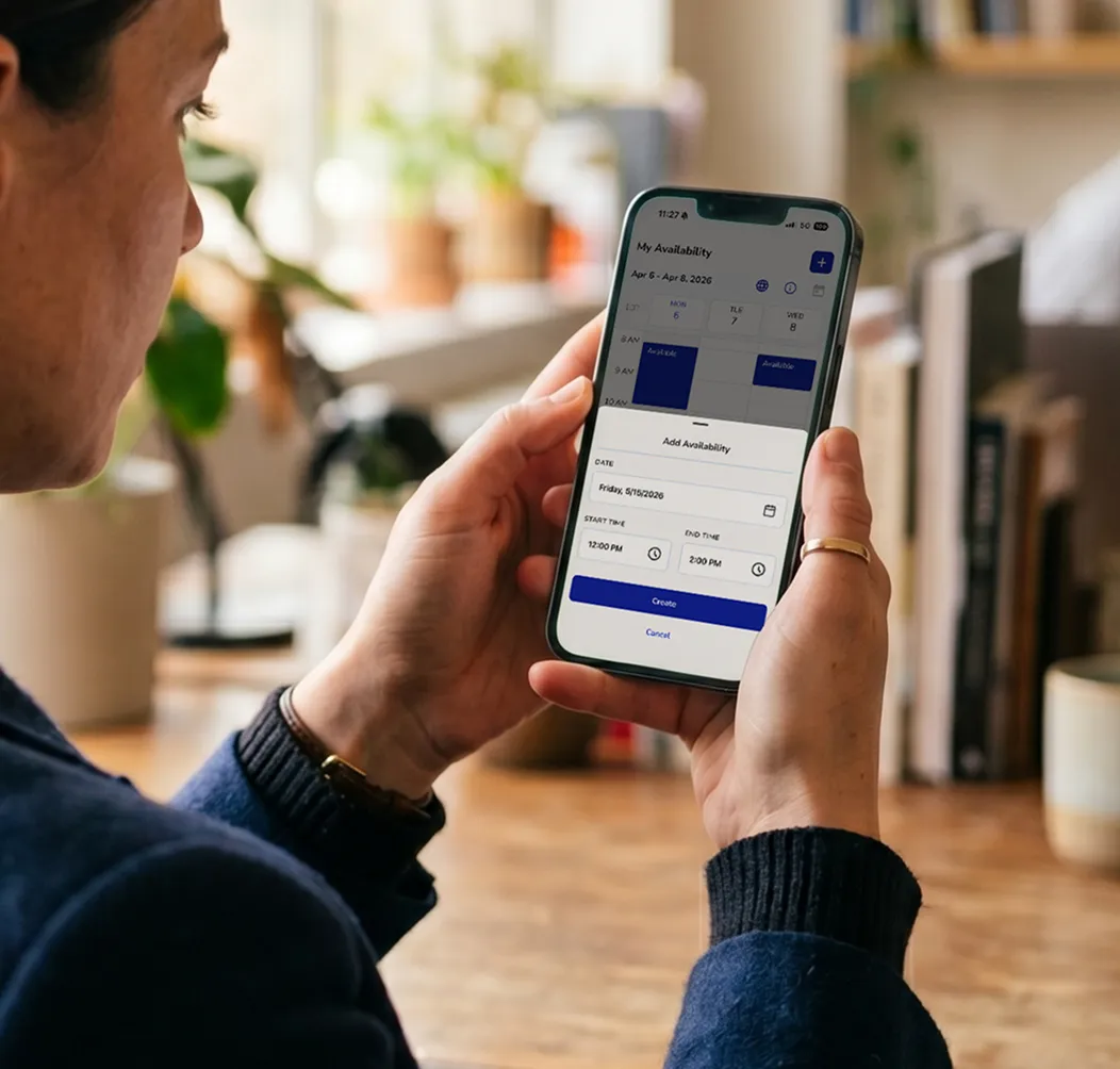 Person holding a smartphone displaying a scheduling app with availability set for Friday, May 15, 2026, from 12:00 PM to 2:00 PM.