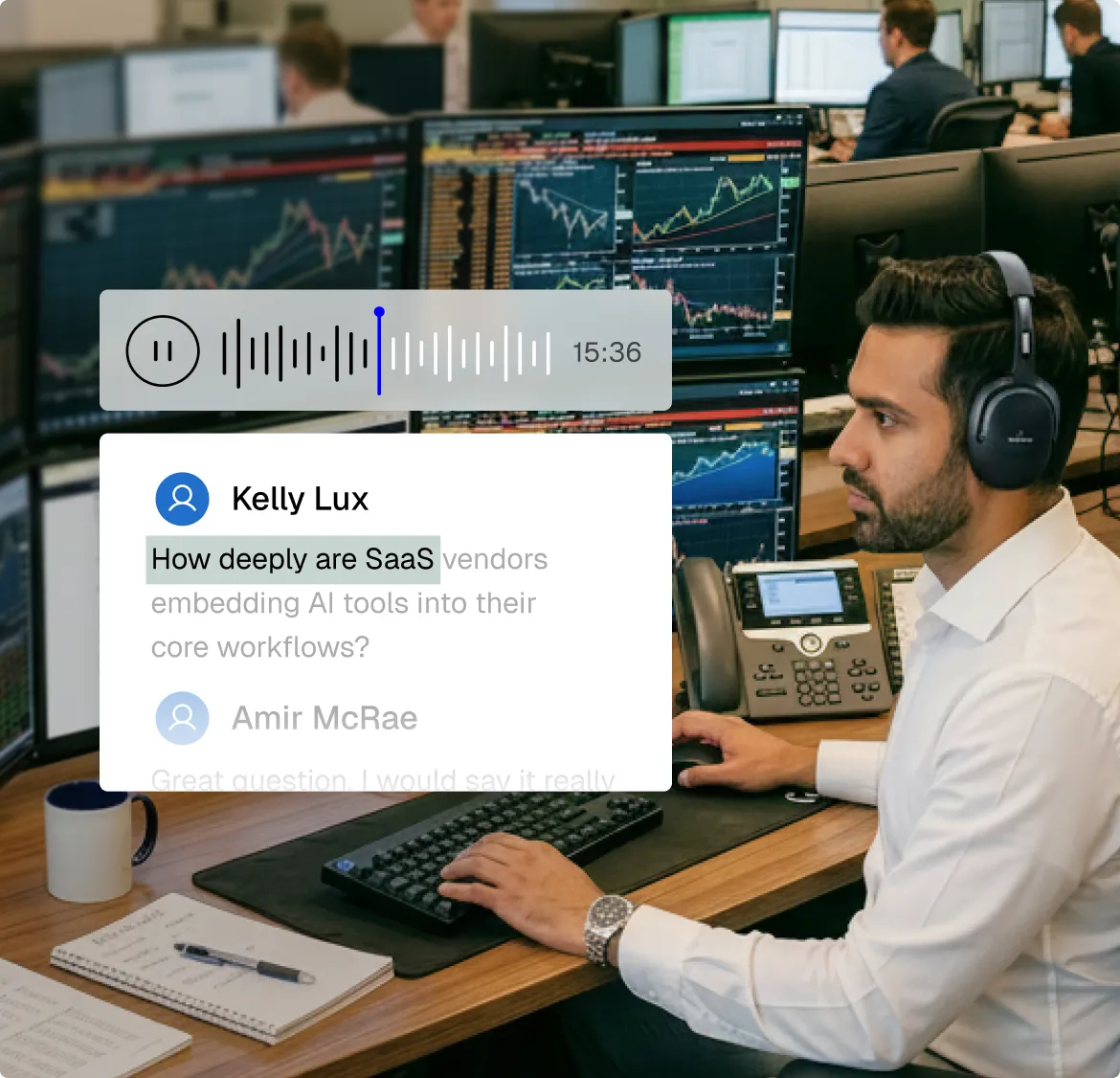 Man with headphones working at a desk with multiple computer monitors displaying stock charts and data, with a phone and notebook nearby.