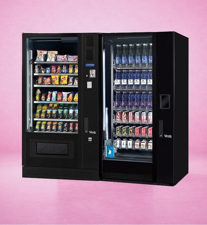 Schwarzer Snack- und Getränkeautomat mit verschiedenen Süßigkeiten und Flaschengetränken vor rosa Hintergrund.