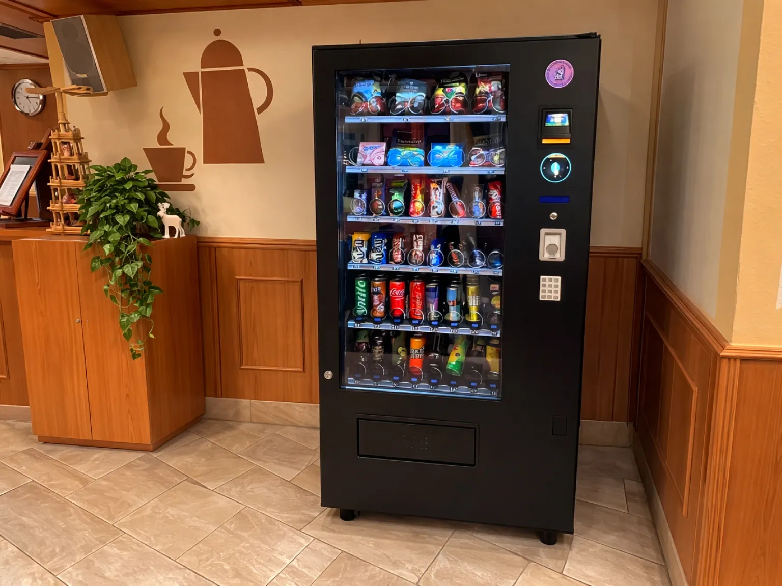 Schwarzer Verkaufsautomat mit Snacks und verschiedenen Getränken vor rosa Hintergrund.