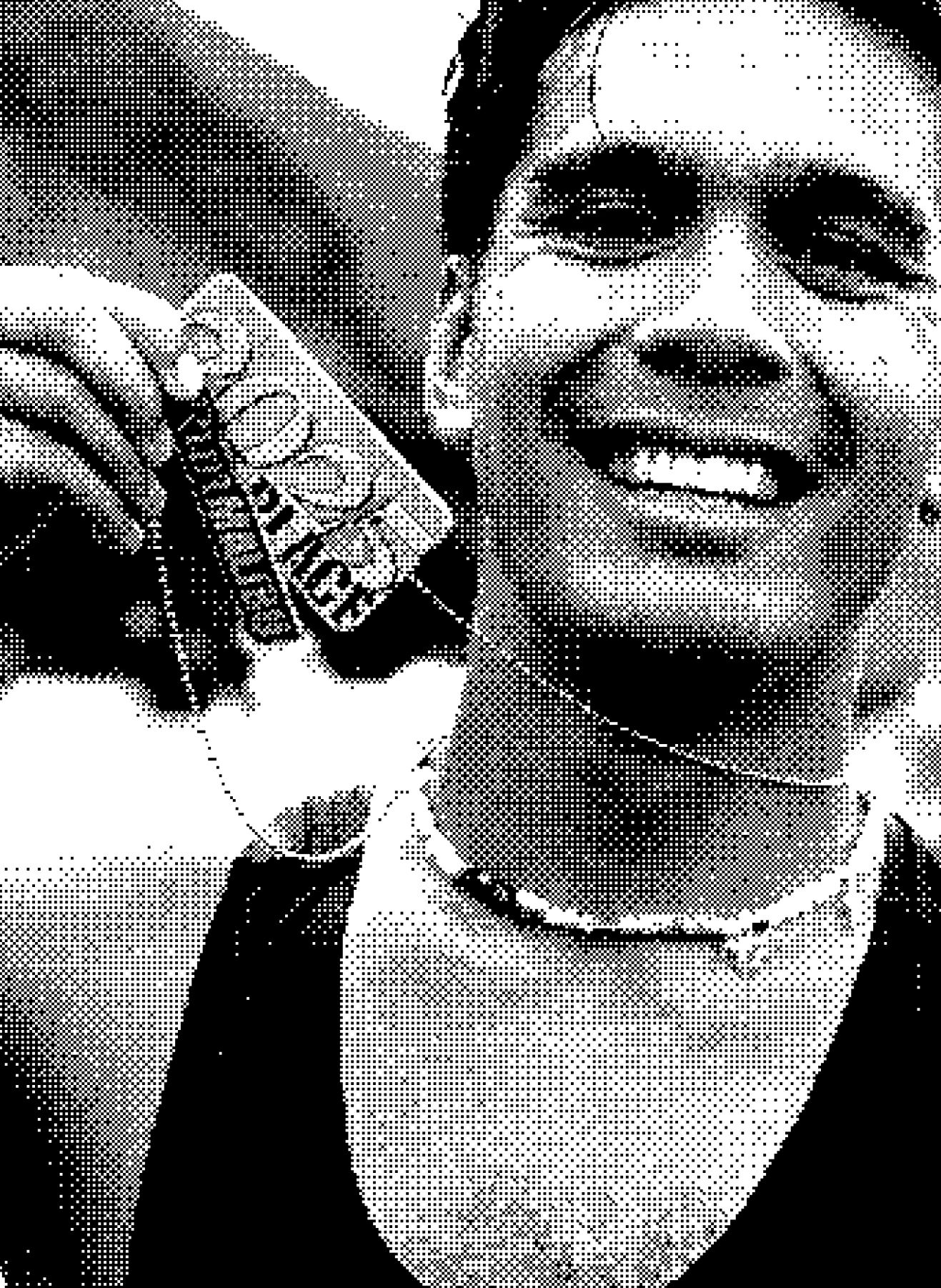 Smiling man wearing a tank top holds up a dog tag medal with the word 'COURAGE' on it.