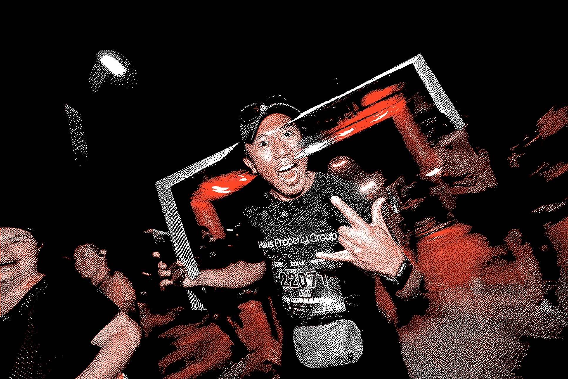 Excited man wearing race bib 22071 making rock hand sign at night race event with crowd.