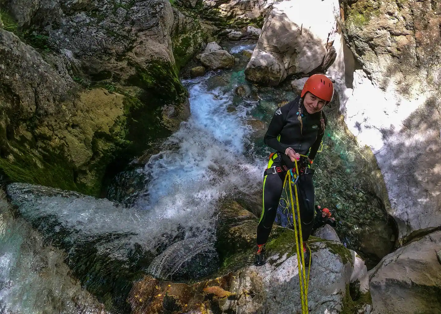 Excited woman rappelling down Hrčavka waterfall guided by certified local expert, canyoning adventure in Sutjeska National Park Bosnia and Herzegovina
