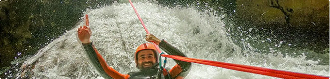 Thrilled man rappelling down Hrčavka canyon waterfall on rope, loving every second of canyoning adventure in Sutjeska National Park Bosnia