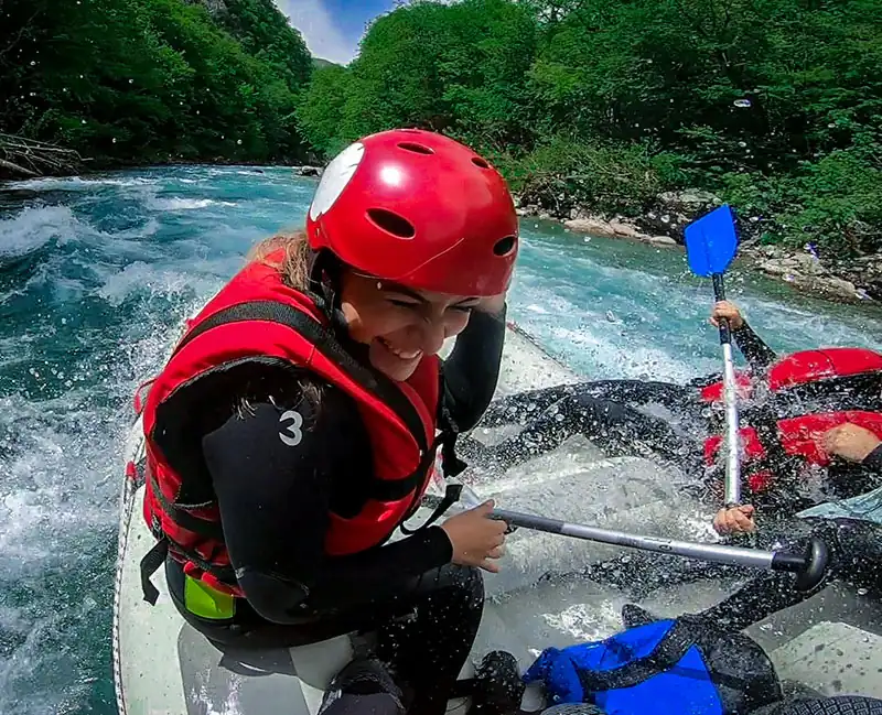 Excited young woman white water rafting on Tara River, adventure tour Bosnia and Herzegovina