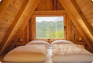 Cozy wooden cabin interior with double bed and mountain view window, Outdoor Tara accommodation Sutjeska