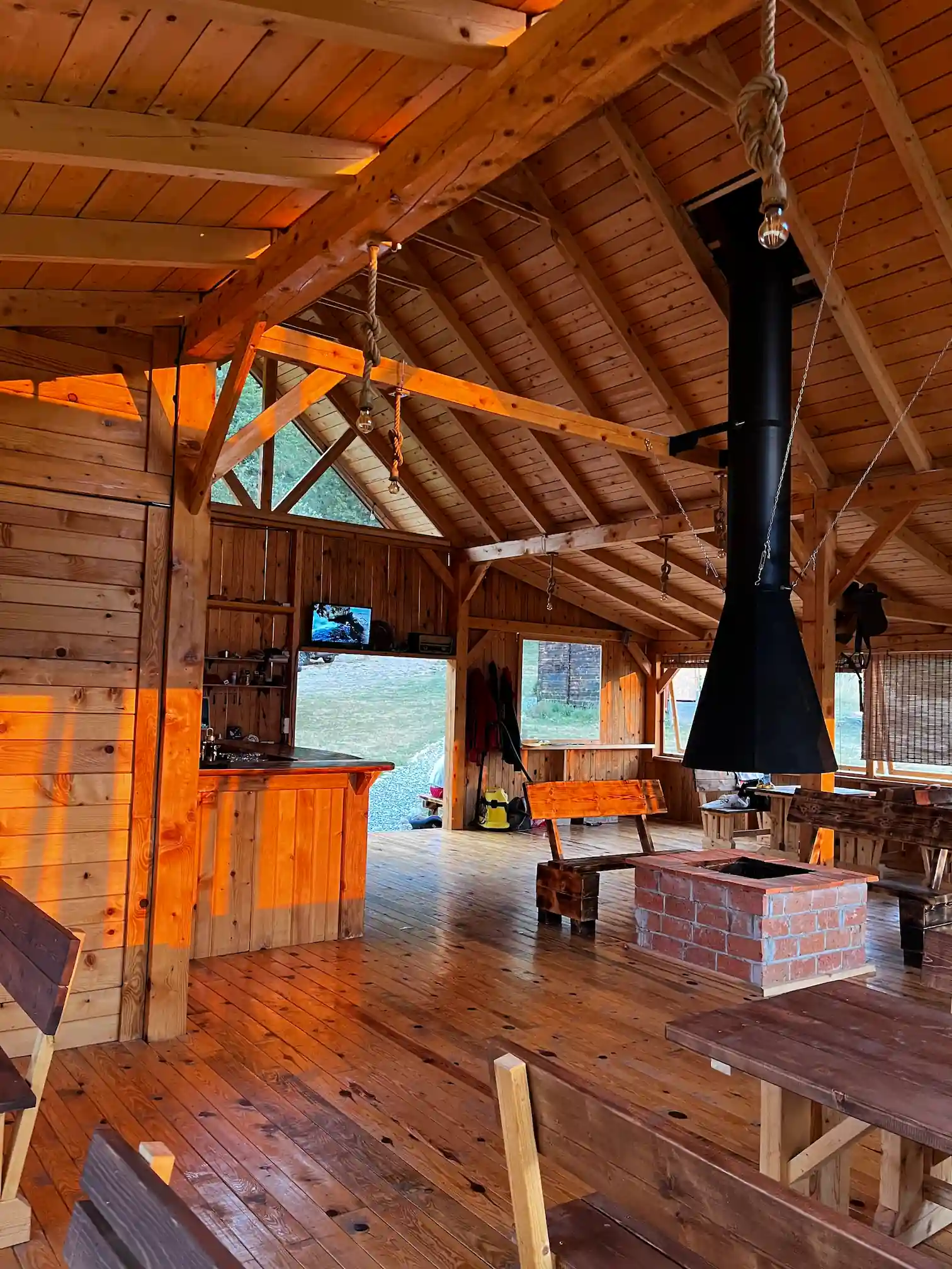 Cozy indoor fireplace area at Outdoor Tara restaurant during golden hour, mountain camp Bosnia