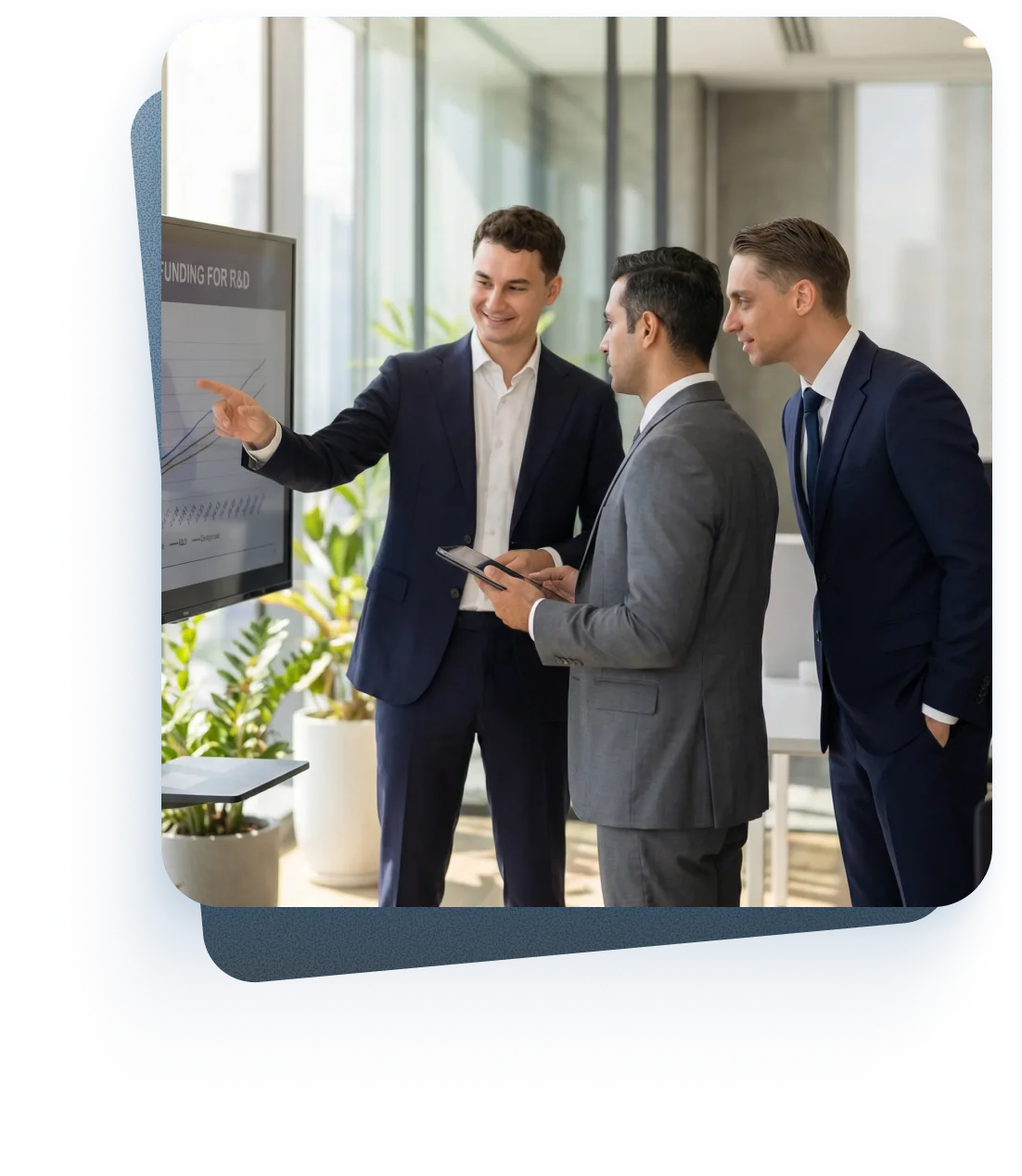 Drei Männer in Anzügen unterhalten sich lächelnd in einem modernen Büro mit großen Fenstern und Stadtblick.