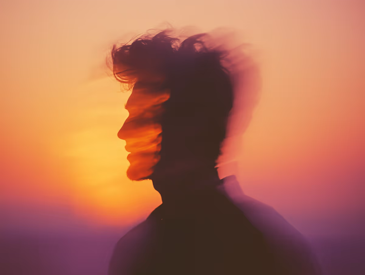Double exposure silhouette of a man with blurred motion against a vibrant sunset background.