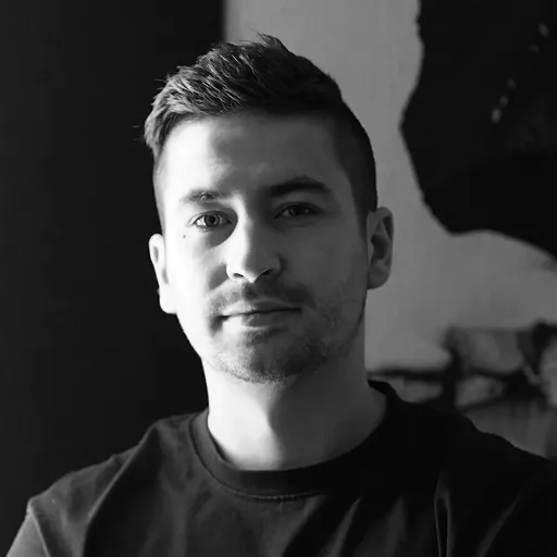 Black and white close-up portrait of a man with short hair and a slight smile looking at the camera.