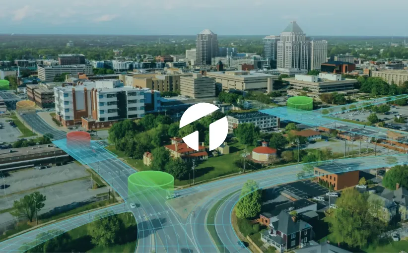 Aerial view of a cityscape with roads and buildings, showing digital overlays of traffic flow and data visualization.