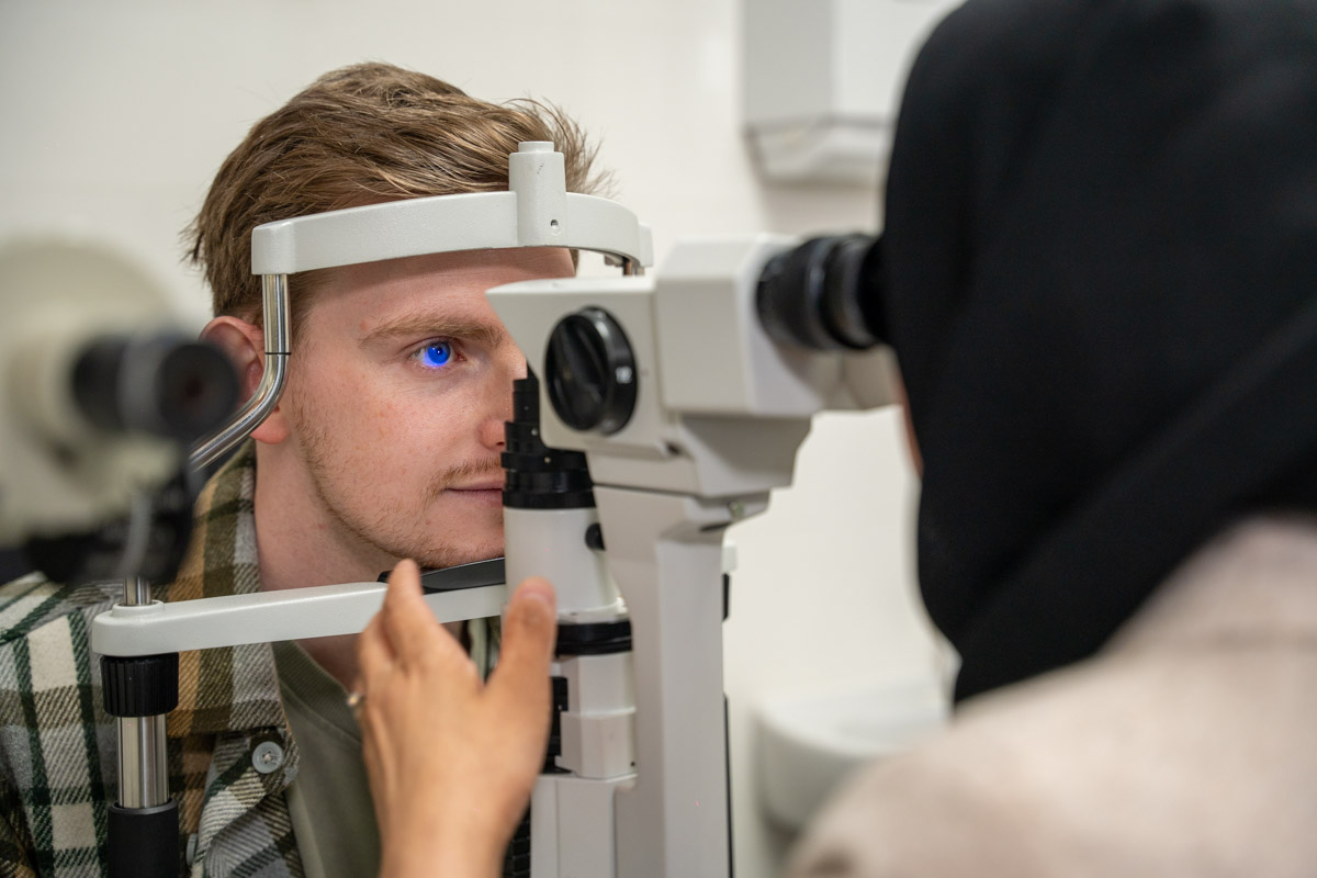 Optometrist using diagnostic equipment during eye exam