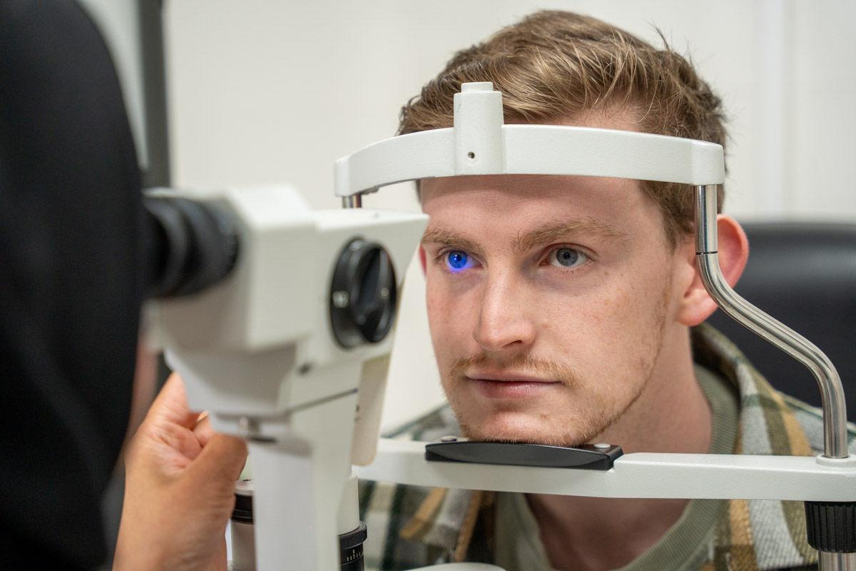 Optometrist using ophthalmoscope headband to examine patient's eye