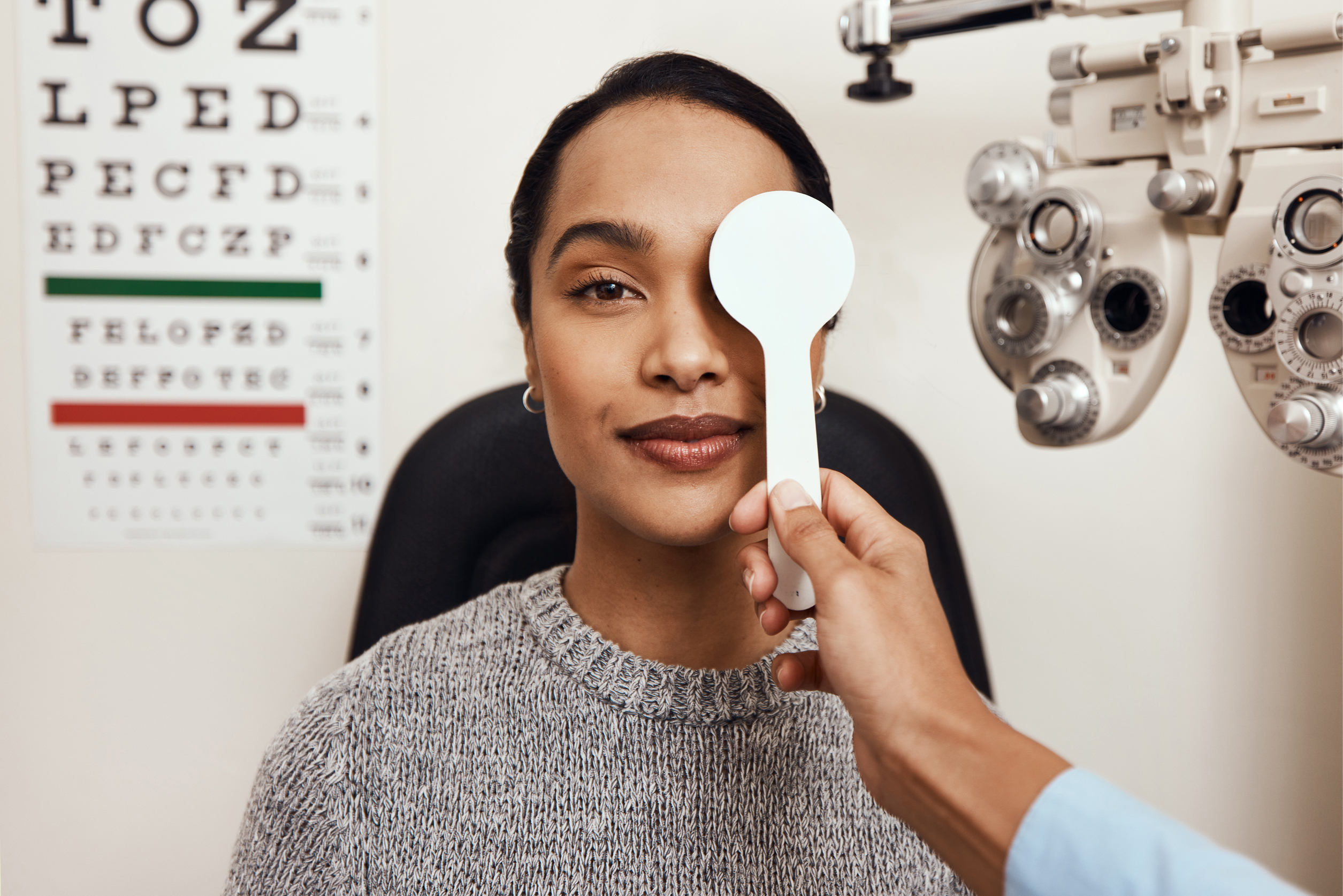 Woman at eye exam with vision testing equipment and phoropter in background