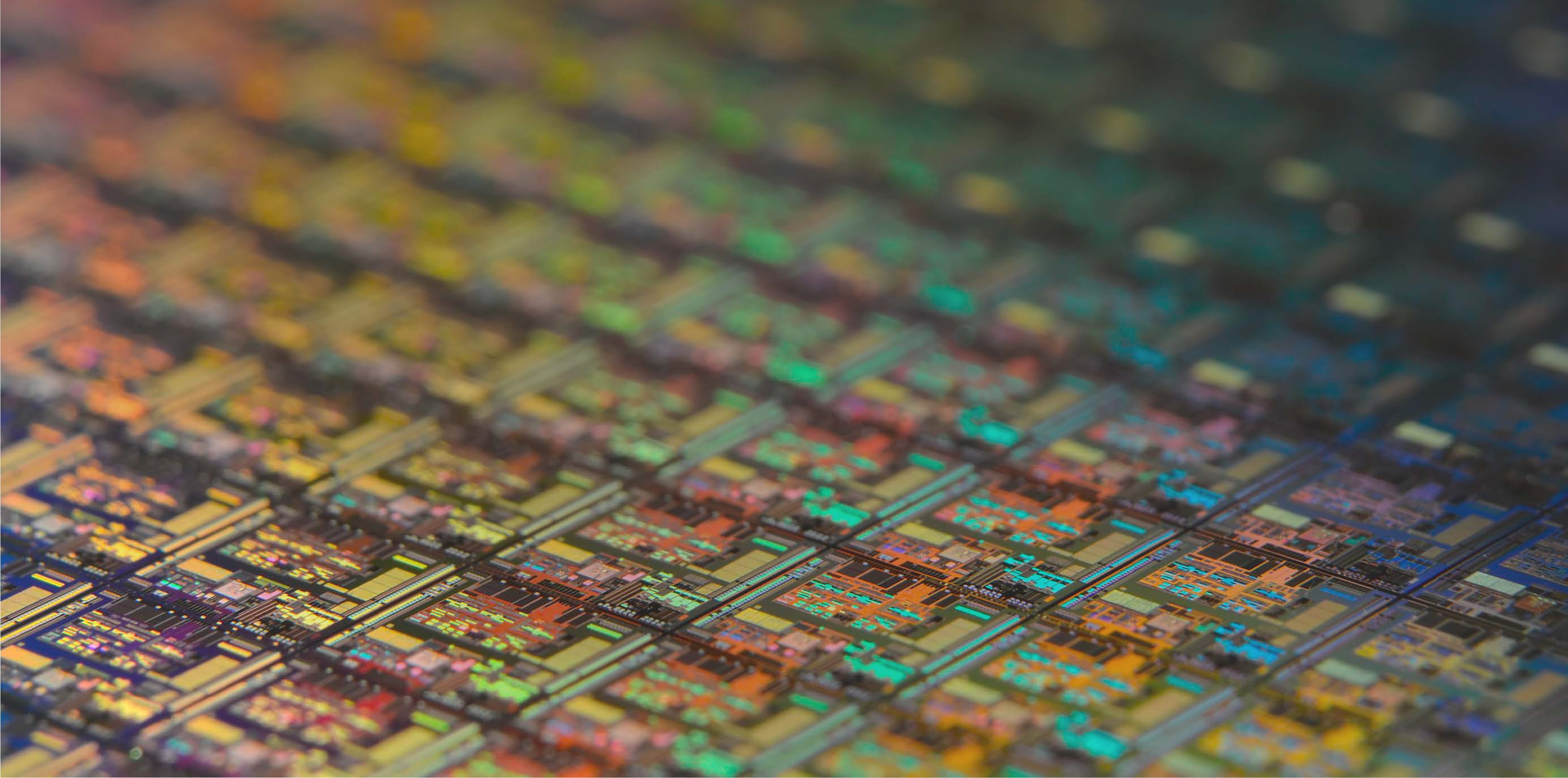 Close-up of a colorful, reflective microchip surface with intricate circuit patterns.