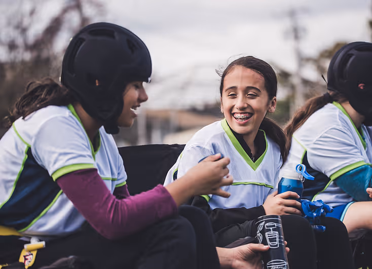 Young girls speak on the sideline of a flag football game