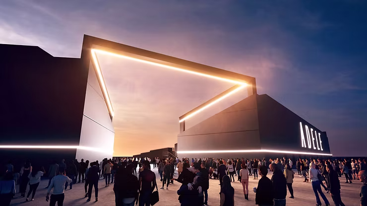 Crowd gathers outside a large temporary structure venue at dusk, with illuminated architectural lines.