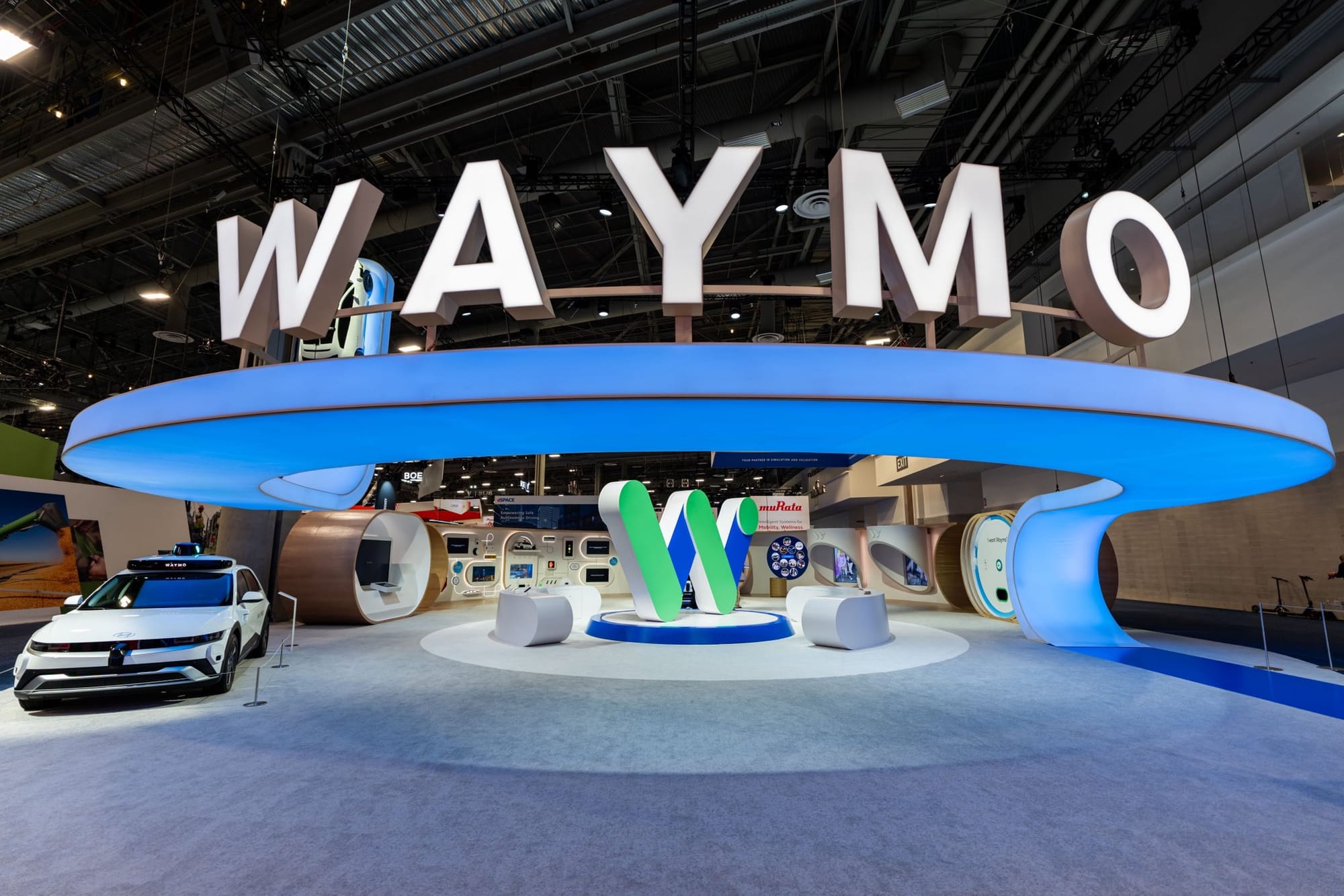 Waymo exhibit at CES 2026 with a vehicle suspended above the 7,000-square-foot booth, designed by NVE Experience Agency