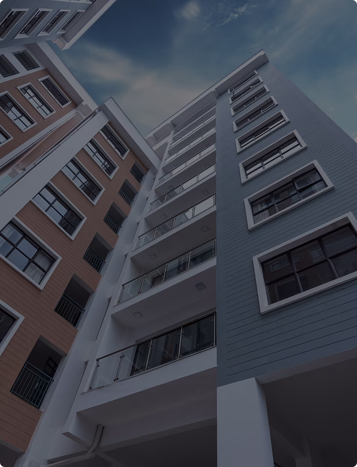 Vue en contre-plongée de plusieurs immeubles modernes avec balcons en verre sous un ciel partiellement nuageux.