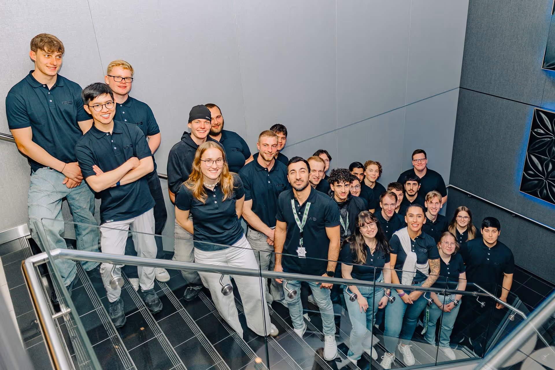 30 Auszubildende ("Gradiatoren") posieren auf einer Treppe