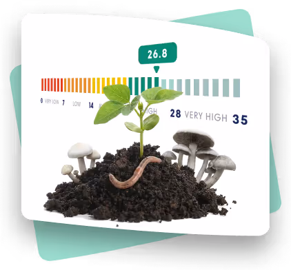 Seedling in dark soil with earthworm and mushrooms under a moisture meter reading 26.8 on a colored scale.