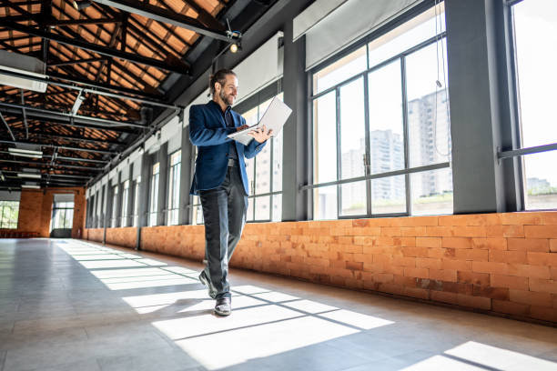 A property manager holding a laptop walks through an empty floor of a commercial office building